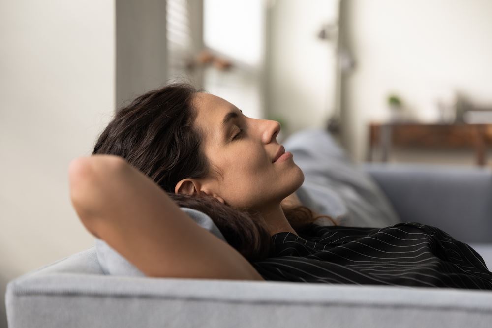 Woman relaxing on couch after getting an HVAC humidifier installation.